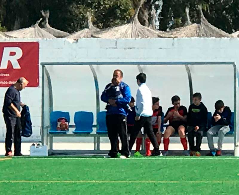 Ángel Sánchez dirigiendo a los infantiles del Montemayor con su hijo en brazos.