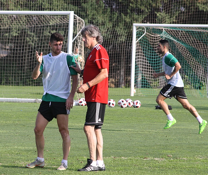 El entrenador blanquiverde, Enrique Martín, hablando con el jugador Javi Flores.