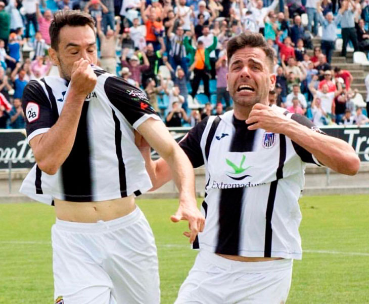 Guzmán besando el escudo del club de su tierra celebrando un gol junto a un compañero
