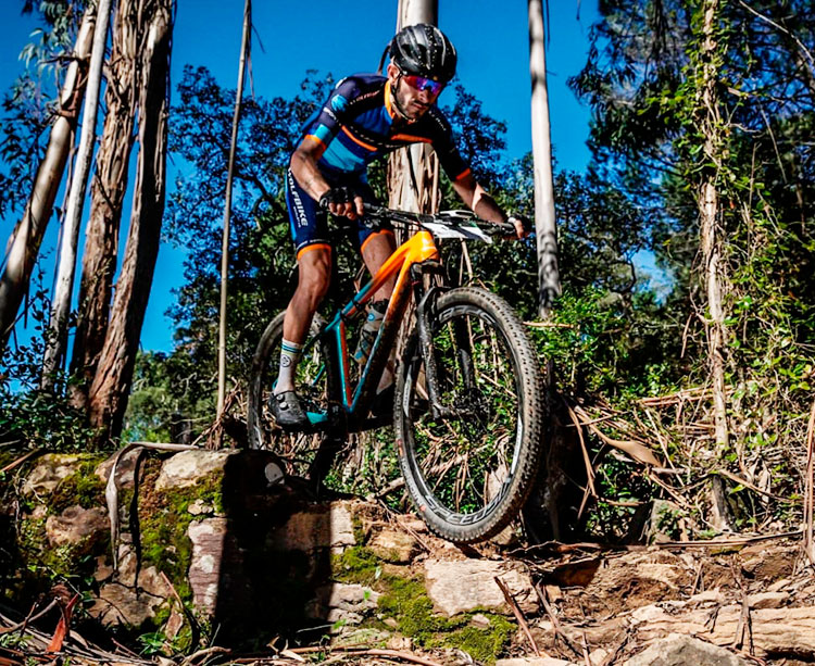 Víctor Manuel Fernández descendiendo con su bicicleta por una zona de arboledas y rocas