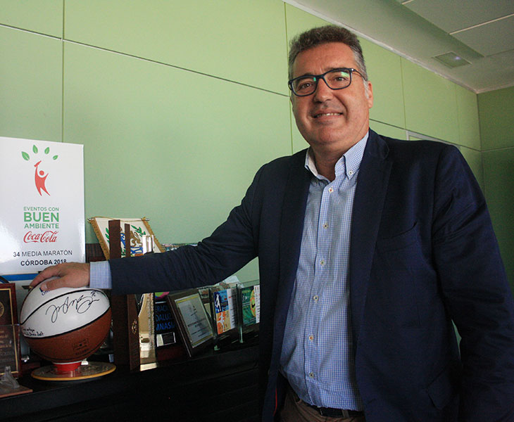 Manuel Torrejimeno posando junto a un balón de baloncesto y otros obsequios de eventos deportivos que pasaron por Córdoba en el pasado