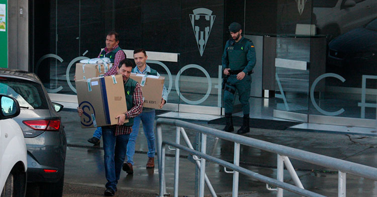 Tres agentes de la policía judicial sacando cajas de El Arcángel con un guardia civil al fondo