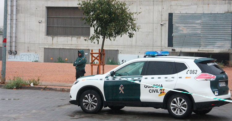 Un guardia civil custodia la zona acotada con una pintada al fondo pidiendo la marcha de Jesús León