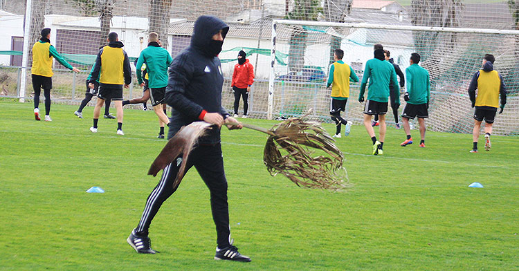 Raúl Agné trasladando una rama de las palmeras que el viento llevó al terreno de juego.