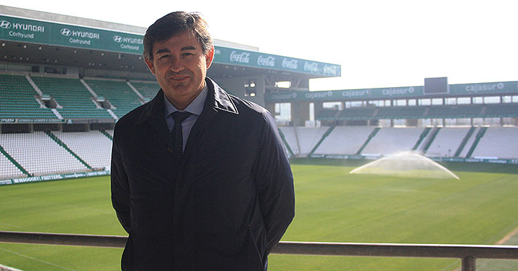 Javier González Calvo con El Arcángel de fondo mientas los aspersores riegan el césped.