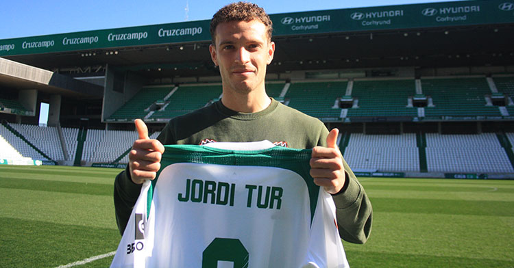 Jordi Tur muestra sus pulgares a la cámara de Cordobadeporte.com sosteniendo la camiseta balanuiverde con su nombre.