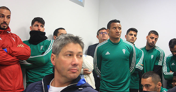 Alfonso Serrano, sentado en los asientos de la sala de prensa, con varios jugadores al fondo y el consejero delegado, Javier González Calvo.