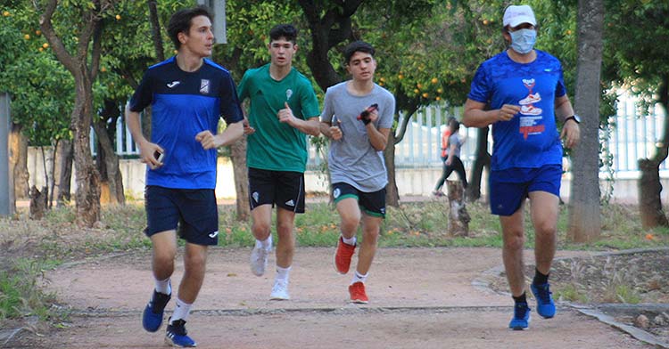 Varios atletas corren por el circuito de El Tablero con un joven integrante de las categorías inferiores del Córdoba CF.