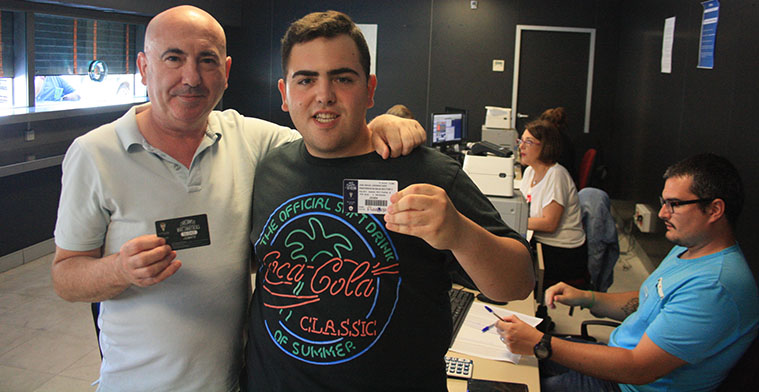 Padre e hijo mostrando sus carnets de abonados renovados en el pasado curso.