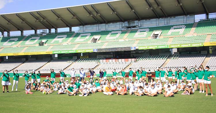 El medio centenar de chavales del Campamento urbano la Puerta Verde sobre el césped de El Arcángel junto a Juanito y Javier González Calvo.