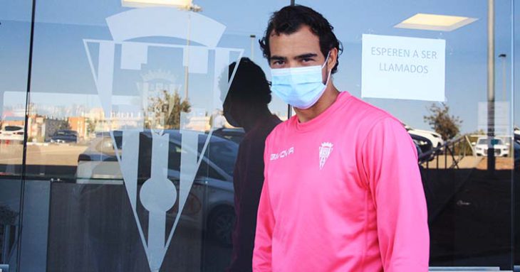 Miguel de las Cuevas posando junto al escudo del Córdoba con su mascarilla de la nueva normalidad.