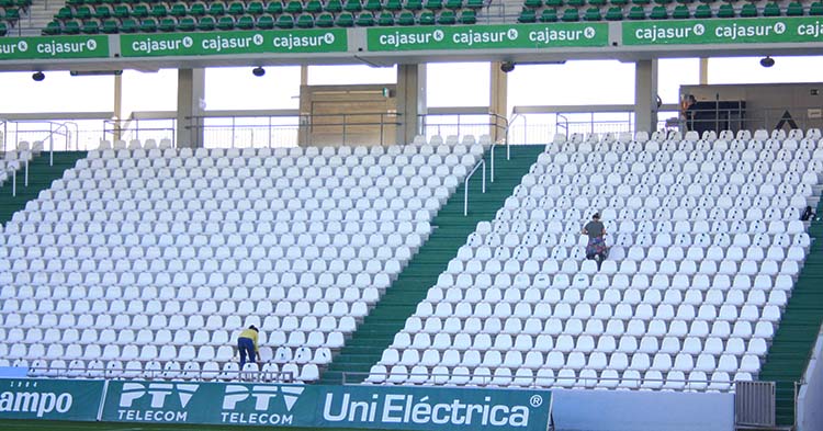 Las operarias del Córdoba señalizando los asientos de la grada de Fondo Sur con la distancia de seguridad reglamentaria de cara al debut liguero ante el Lorca.