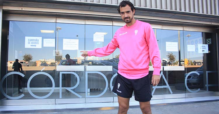 Miguel de las Cuevas señalando el nombre de su club en la cristalera de acceso a las oficinas de El Arcángel.