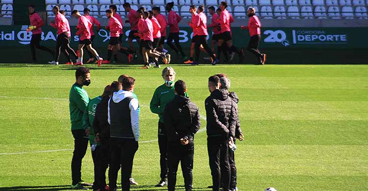 Pablo Alfaro dirigiéndose a su cuerpo técnico mientras los jugadores hacen carrera continua al fondo.