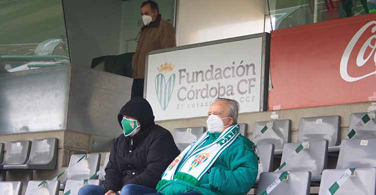 El cartel de la Fundación con un par de cordobesistas en la grada en el partido ante el Getafe, el último que permitió asistencia de público a El Arcángel