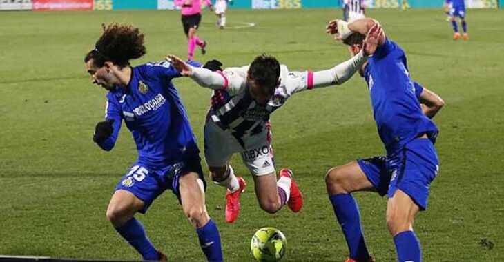 Un jugador del Real Valladolid cae entre Cucurella y otro jugador del Getafe.