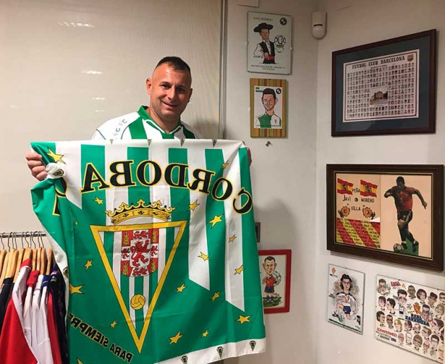Javi Moreno mostrando una bandera del Córdoba CF en su casa de Picasent.