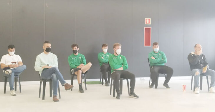 El cuerpo técnico de Germán Crespo siguiendo su presentación desde el fondo del salón de actos.