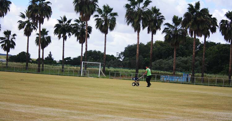 Un operario trabajando sobre el campo primero de la Ciudad Deportiva tras retirarse su césped.