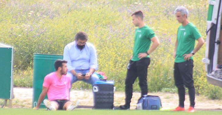 Carlos Puga sentado sobre el césped en la banda ante Javier González Calvo y el doctor Bretones.