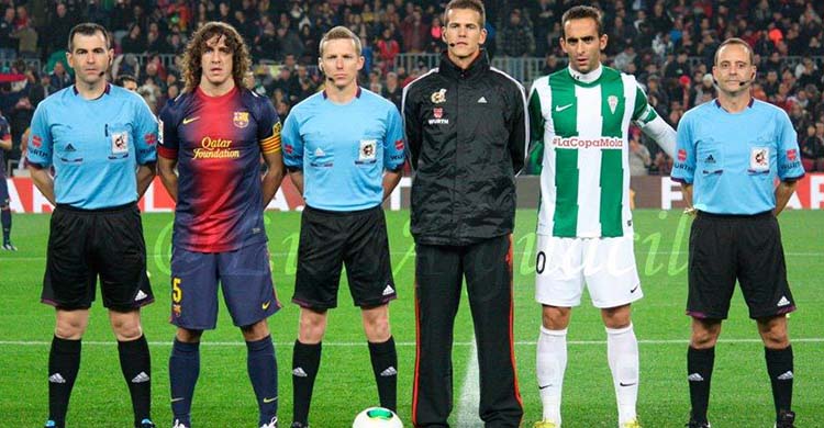 Alberto Aguilar portando el brazalete de capitán del Córdoba CF en el Nou Camp posando con el trío arbitral junto a Puyol.