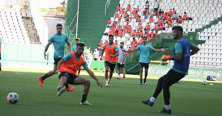 El meta del filial Hankins pasa el balón ante la llegada de Puga, con los niñ@os del Club Mirabueno al fondo en la grada del Fondo Norte.