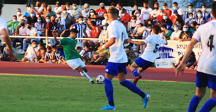 Álex Meléndez centrando desde su puesto de lateral zurdo con la grada abarrotada al fondo de recreativistas.