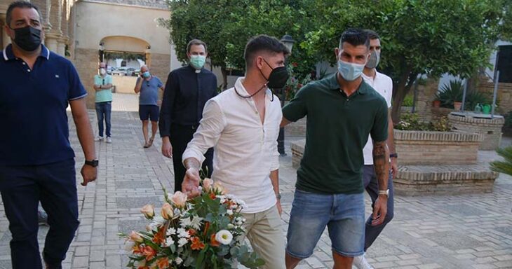 Javi Flores y Willy portando una corona de flores, con Germán Crespo a la izquierda, en la parroquia de Nuestra Señora de la Fuensanta.