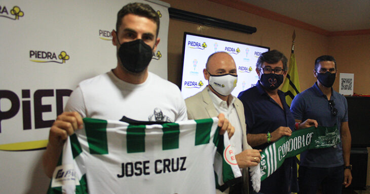 José Cruz mostrando su camiseta en la sede de Piedra durante su presentación acompañado por el director de los supermercados cordobeses junto a Javier González Calvo y Juanito.