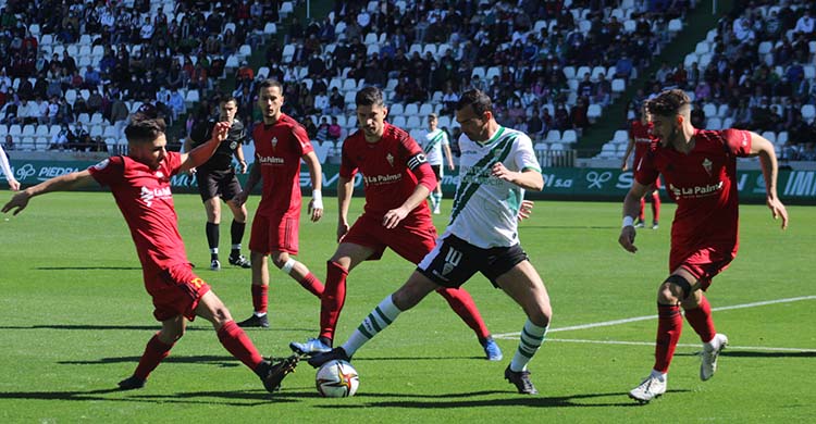 Miguel de las Cuevas controlando un balón rodeado por jugadores del Mensajero.