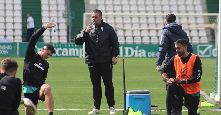 Germán Crespo bebe un sorbo de agua mientras sus jugadores estiran.