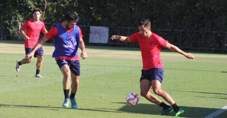 Carracedo superando a Puga con Manolillo al fondo.