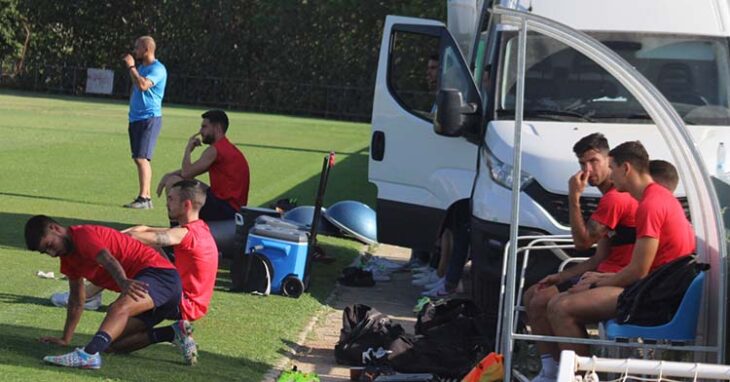 Calderón estira en la banda, mientras Willy, Adri Fuentes y Ekaitz siguen el entreno en el banquillo, con Carlos Daniel y José Cruz al fondo.