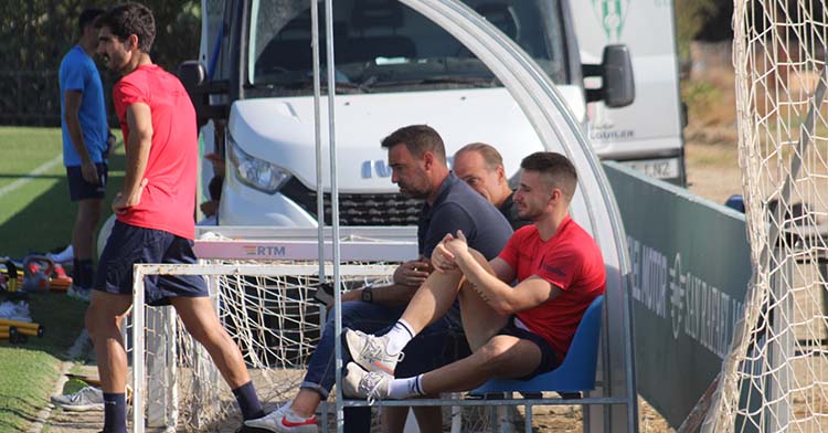 Ekatiz Jiménez siguiendo los entrenamientos desde el banquillo junto a los delegados con Bernardo Cruz al fondo.
