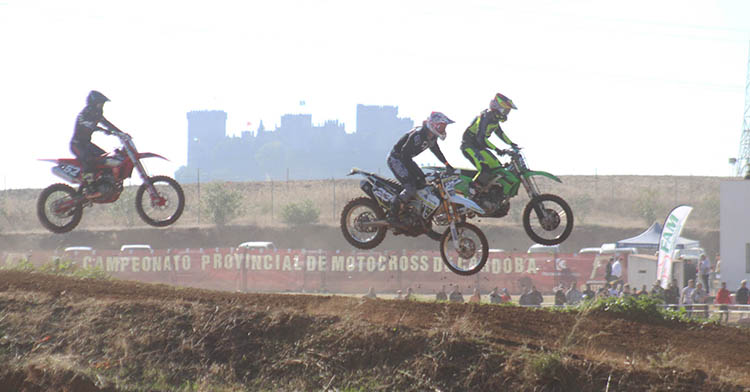 Tres pilotos volando en el circuito de El Pinillo con el Castillo de Almodóvar del Río al fondo.