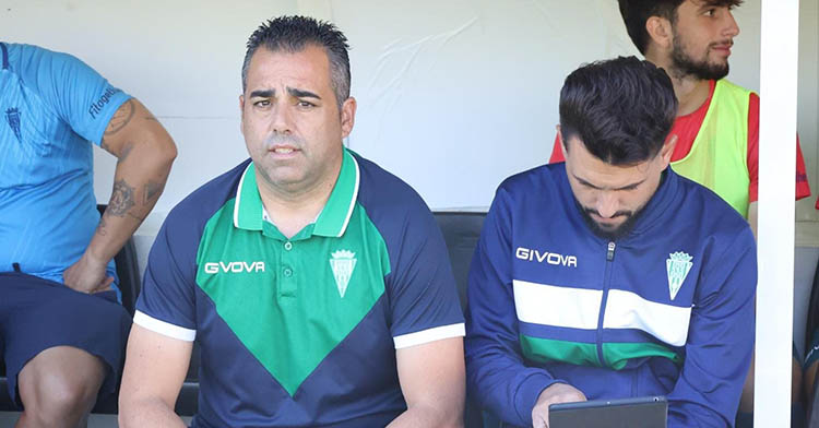 Germán Crespo sentado en el banquillo del Alfonso Murube junto a su segundo, Óscar Ibáñez, con el canterano Christian Delgado al fondo.