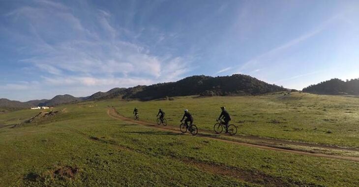 Varios ciclistas paseando por un espectacular paisaje rural.