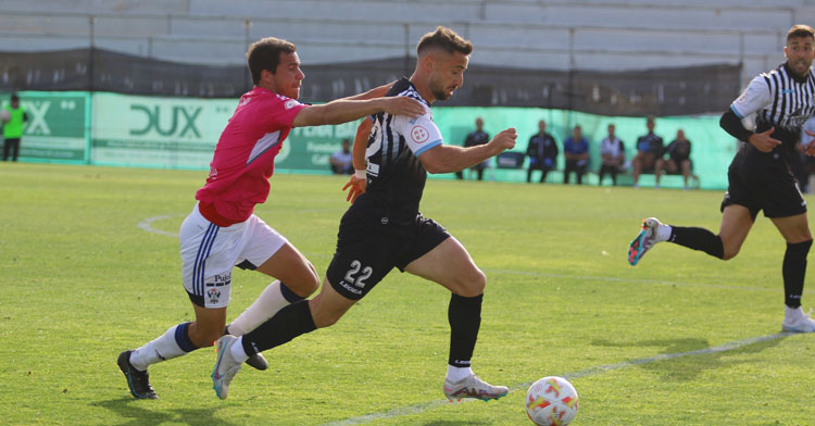 Omar Perdomo conduce el balón perseguido por un rival. Foto: Real Balompédica Linense