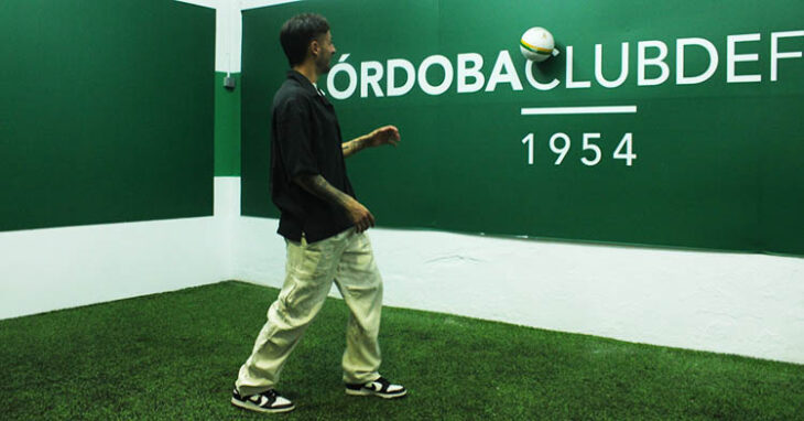 Adri Castellano tocando el balón sobre la pared con el nombre del Córdoba CF.