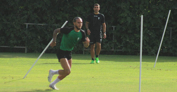 Gudelj sprintando entra las picas con el preparador físico Pablo Gutiérrez al fondo.