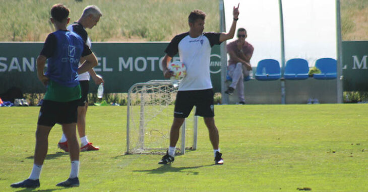 Iván Ania dando instrucciones con Juanito al fondo observándole.