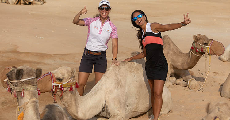 Nuria Iturrioz y Piti Martínez en Riad con varios camellos.