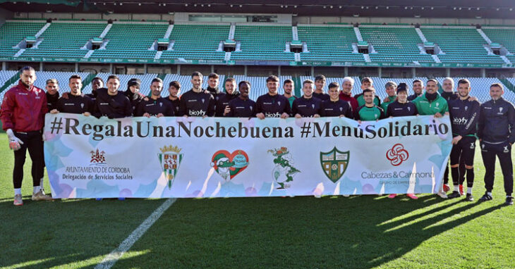 Jugadores y técnicos del Córdoba CF posando con la pancarta de la iniciativa de Cocinillas CCF. Foto: CCF