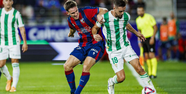 Genaro defendiendo un balón ante un oscense.