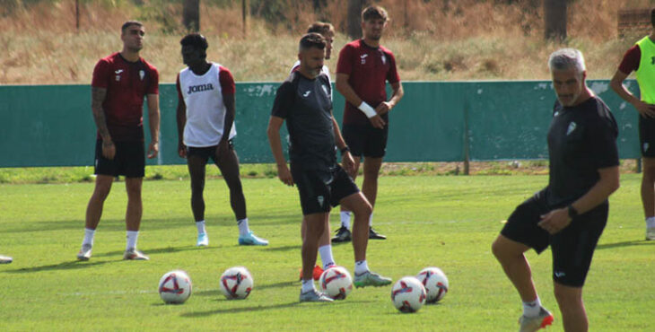 Iván Ania jugando con los balones con varios de sus jugadores a sus espaldas.