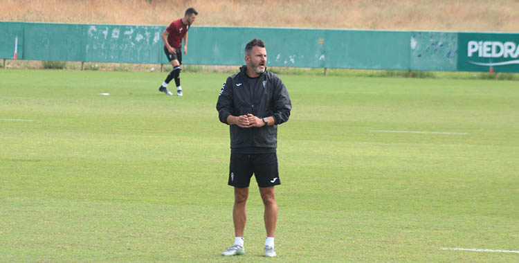 Pensativo, Iván Ania observando a sus jugadores con Adri Lapeña al fondo, su gran aval defensivo para El Molinón.