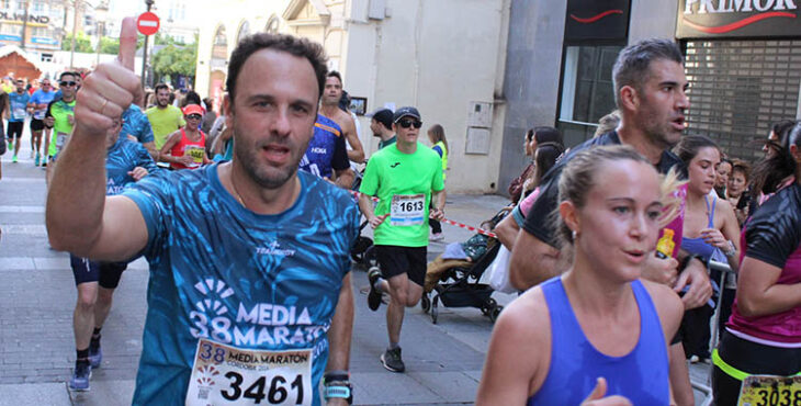 Un atleta popular muestra su pulgar a la cámara de Cordobadeporte junto a otra atleta a su paso por las Tendillas.