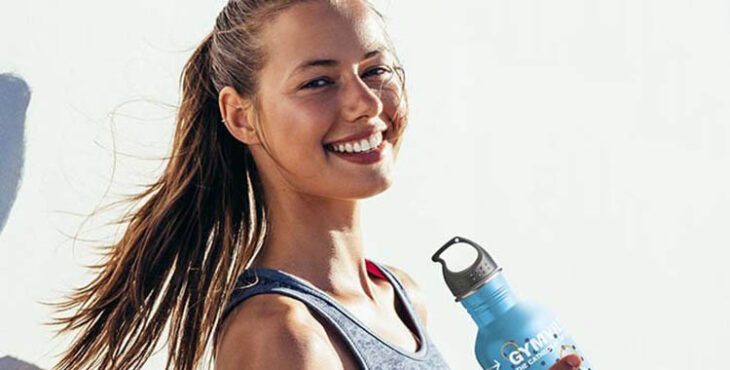 Una chica muestra su botella personalizada del gimnasio.