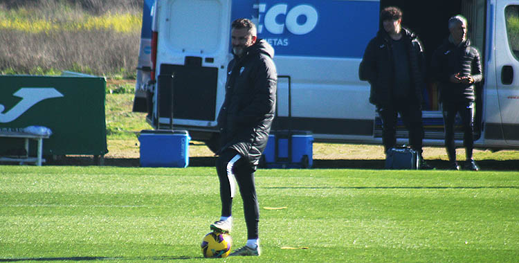 Iván Ania pisando el balón en la Ciudad Deportiva mirando a sus chicos.