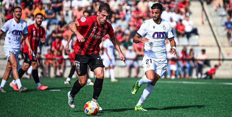 Marcos Pérez conduce la pelota con un rival del cuadro blanco encimándole. Foto: Real Jaén CF